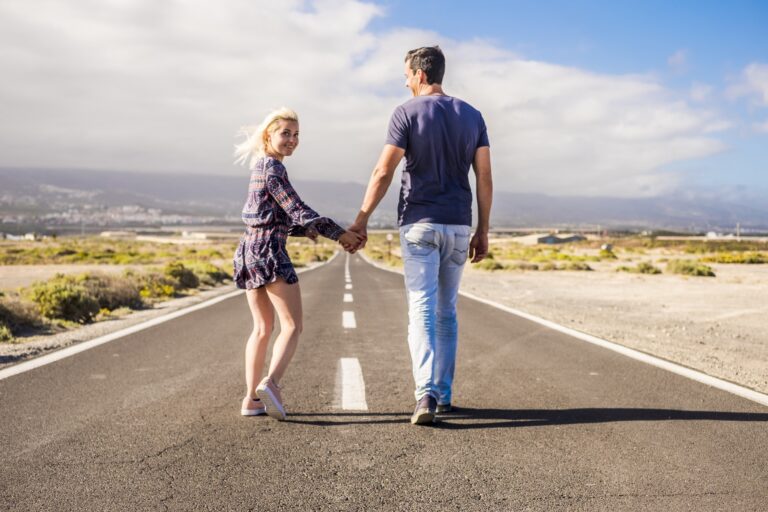 nice caucasian couple in relationship taking hands and walk together long road