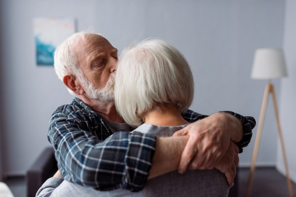 senior man hugging and kissing wife, suffering from alzheimer disease