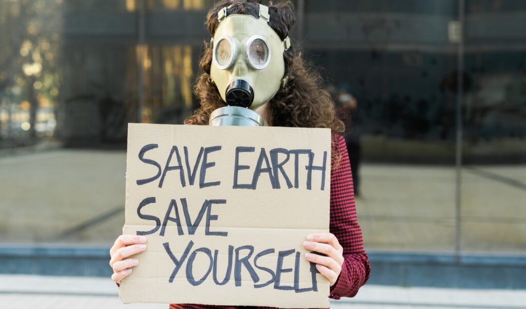 Woman with gas mask and a sign that reads: save earth save yourself. Concept: environmentalism