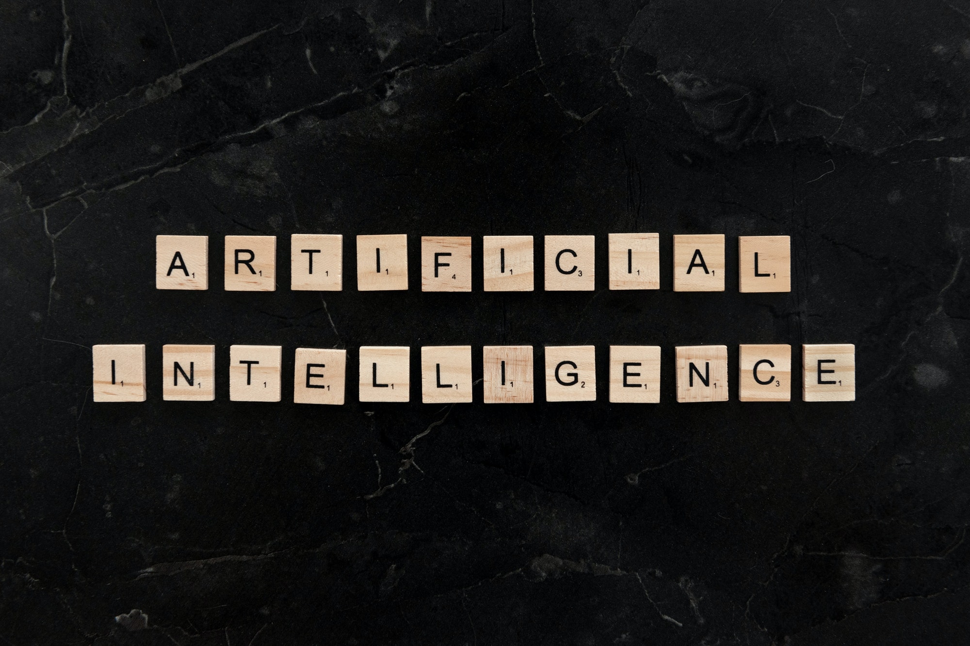 Wooden tiles spelling "artificial intelligence" on black background