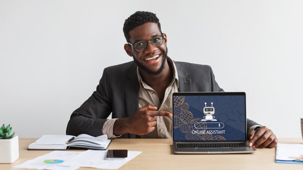 Young black man wearing eyeglasses working on laptop, using chatbot