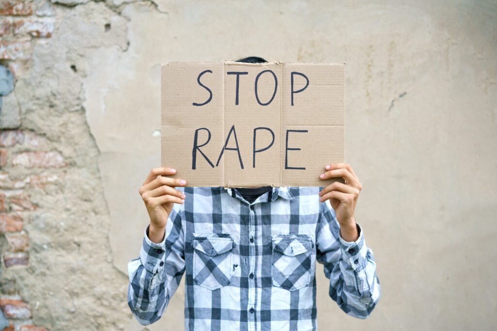 Young man holding cardboard with the inscription stop rape.