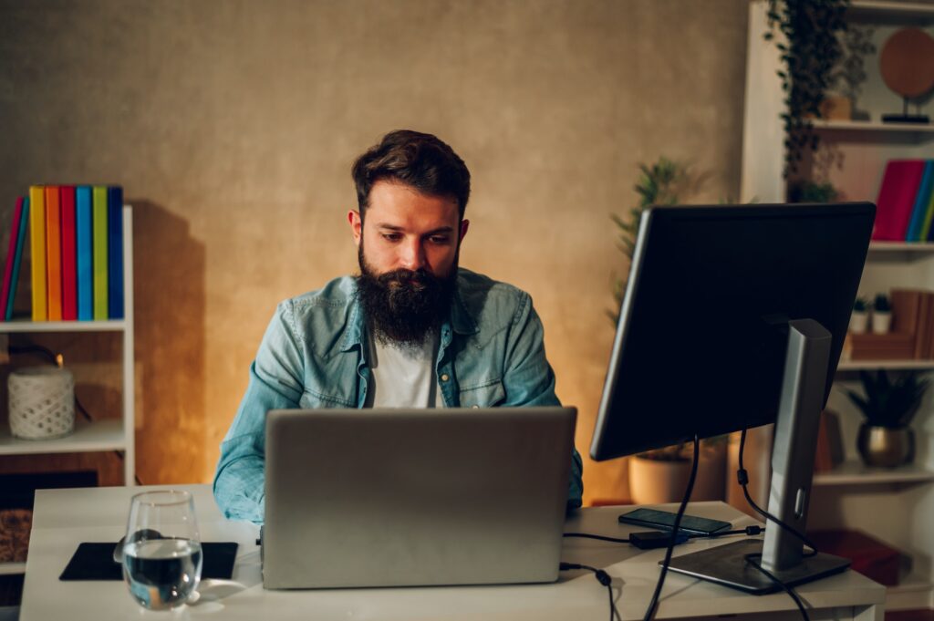 A focused AI web developer is sitting at his home office and coding a new generation of AI web apps.