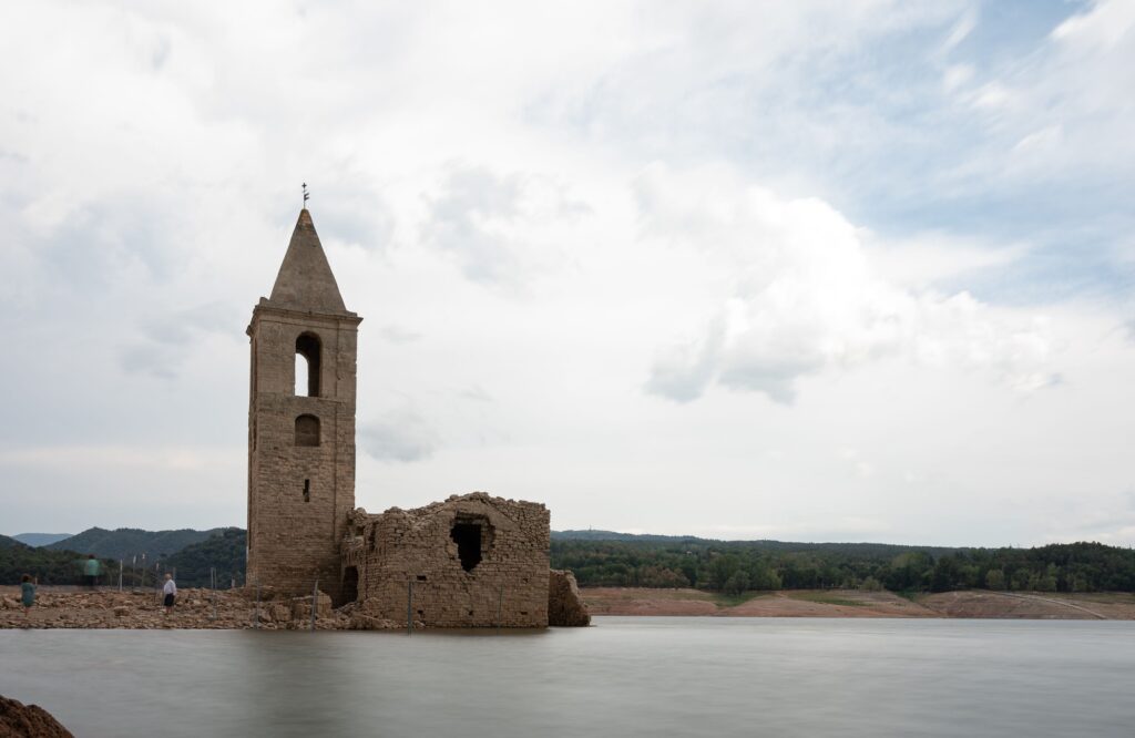 Church of Sant Roma de Sau in the Sau reservoir with silk effect water with people