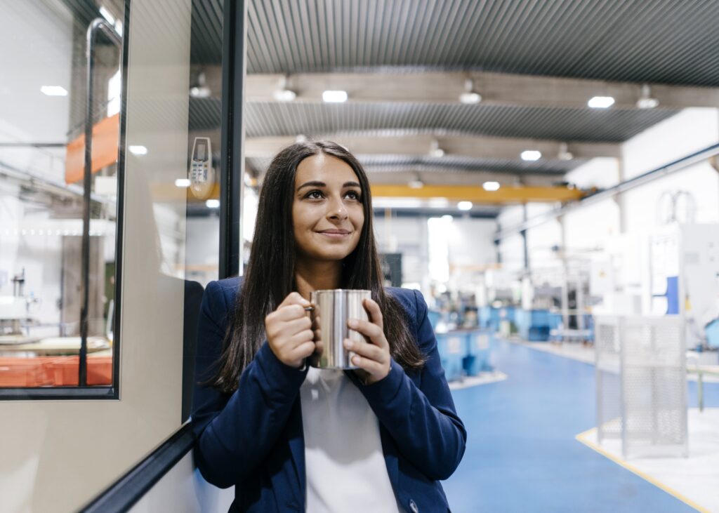 Confident woman working in high tech enterprise, drinking coffee