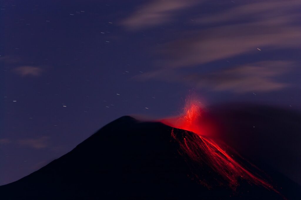 Evening view of fiery eruption of volcano, with lava running down the mountain slopes.