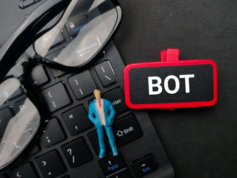 Miniature people and wooden board with the word BOT on black background.