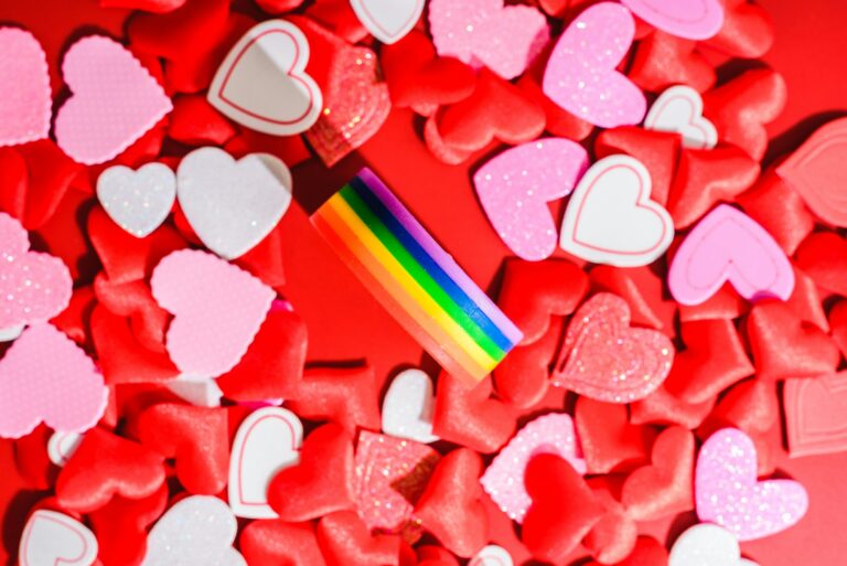 Multicolored LGBT symbol on a background of romantic red hearts, valentines for same-sex couples.