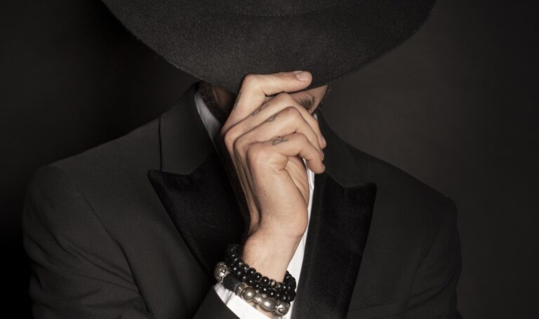 Secret adult mafia boss wearing a suit and covering his head with a fedora hat