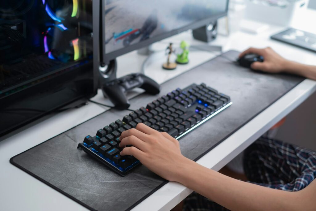 selective focus of a teenager hands playing on a gaming computer, with on a large gray mouse pad