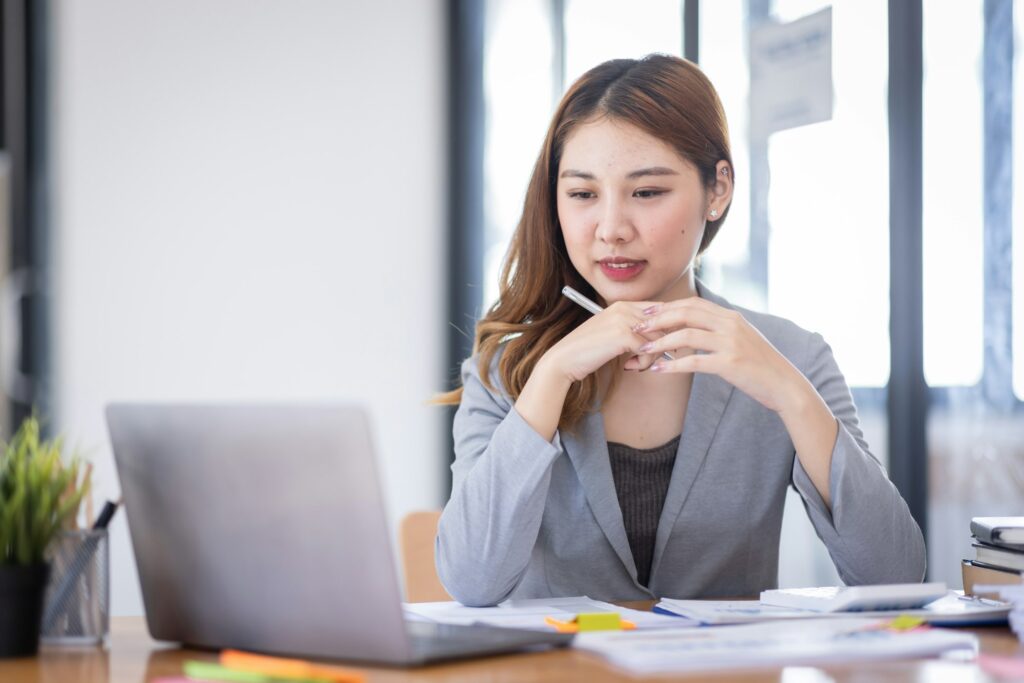 Smiling young Asian business woman executive looking at smartphone using cellphone mobile cell tech,