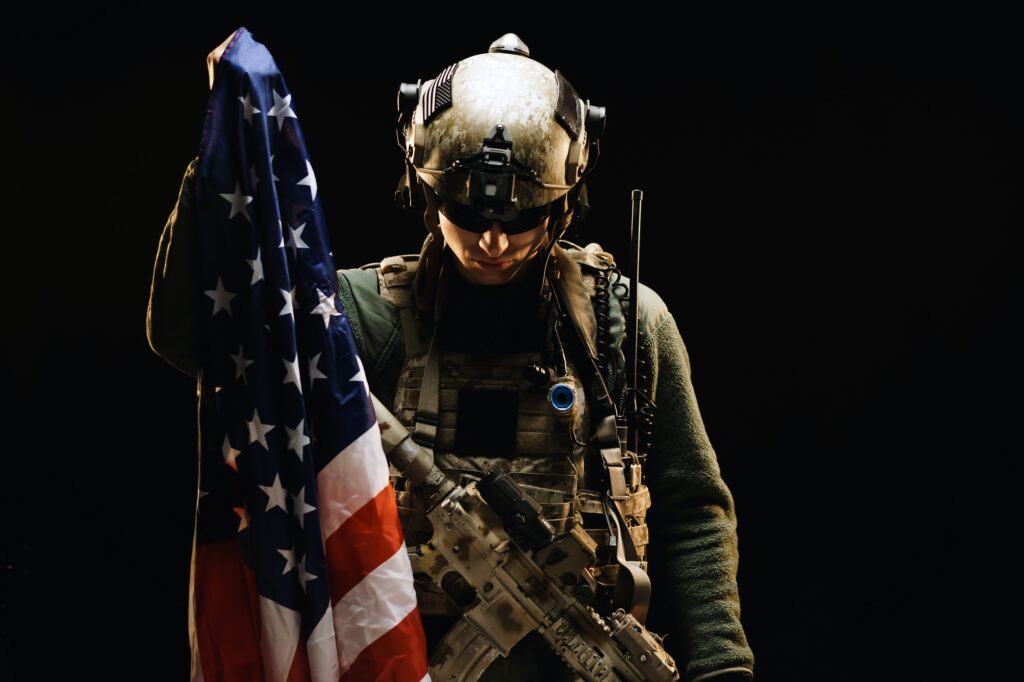 Special forces soldier holding US national flag in the dark