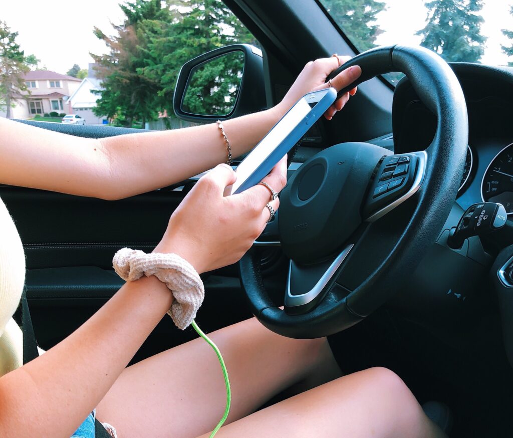 Teenage girl using mobile phone while driving, distracted driving, dangerous drivers