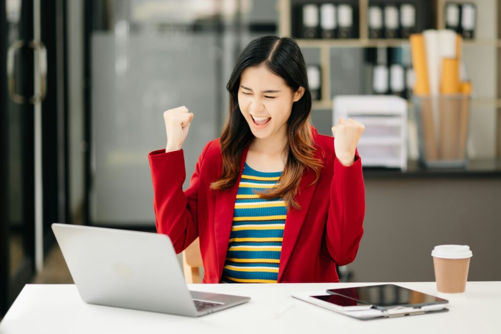 Asian Business woman Talking on the phone and using a laptop with a smile while sitting at office