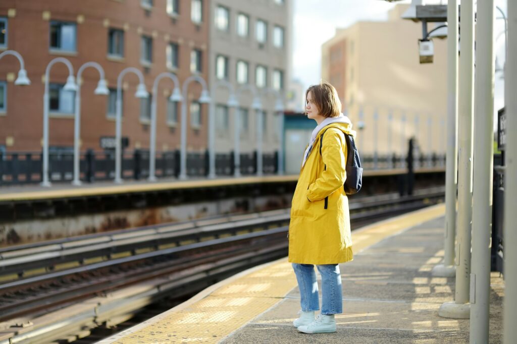 Beautiful young woman is waiting for a train on a platform in the New York subway. Transport of NYC,