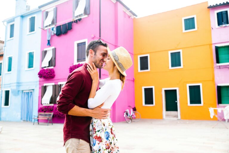 Couple of lovers kissing on city street in front of colorful buildings