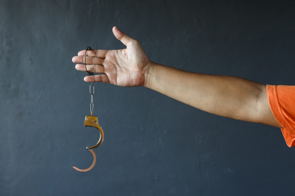 Hand of prisoner holding opened handcuffs. Free from jail or freedom concept