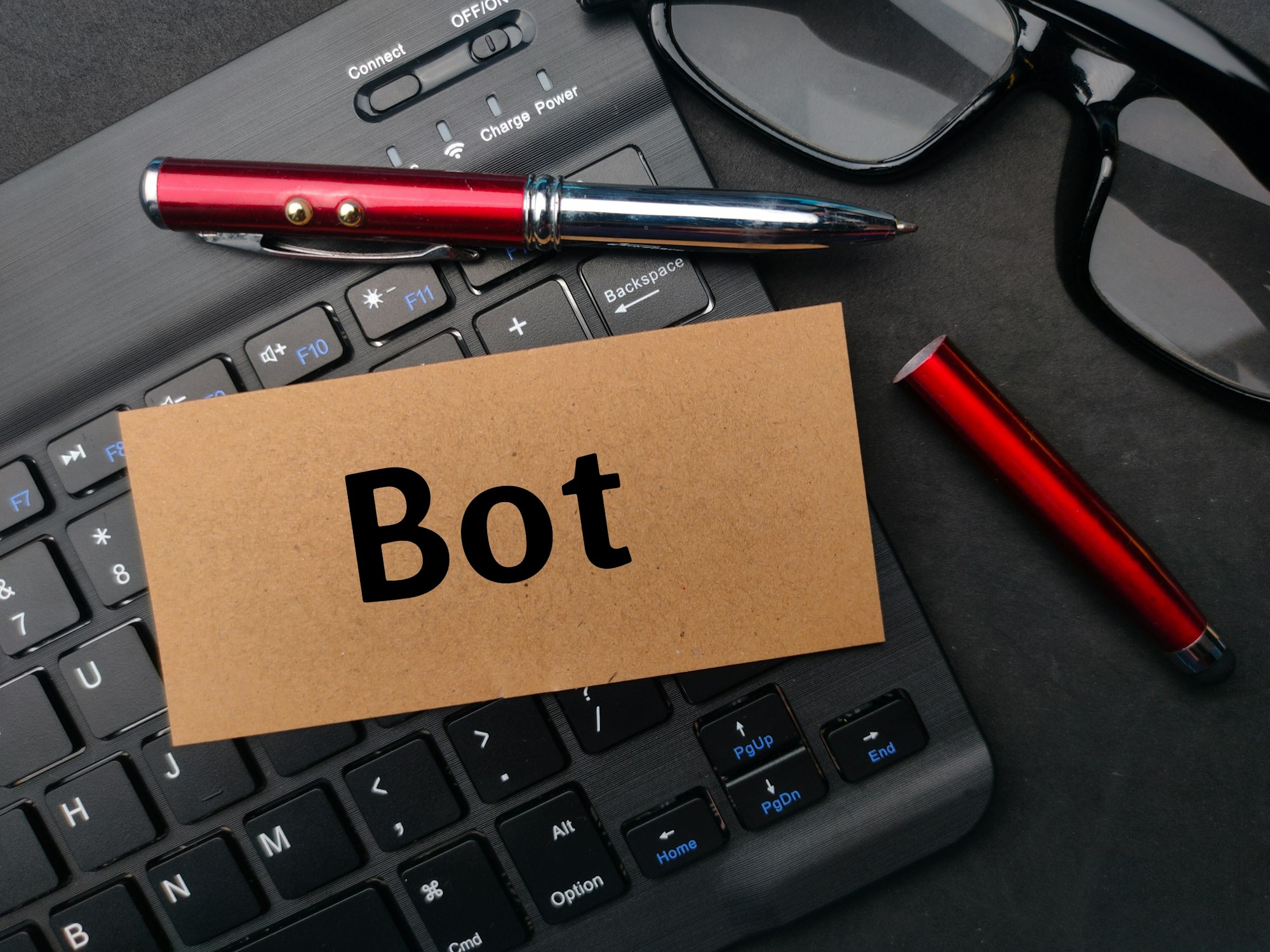 Keyboard and pen with the word BOT on black background.