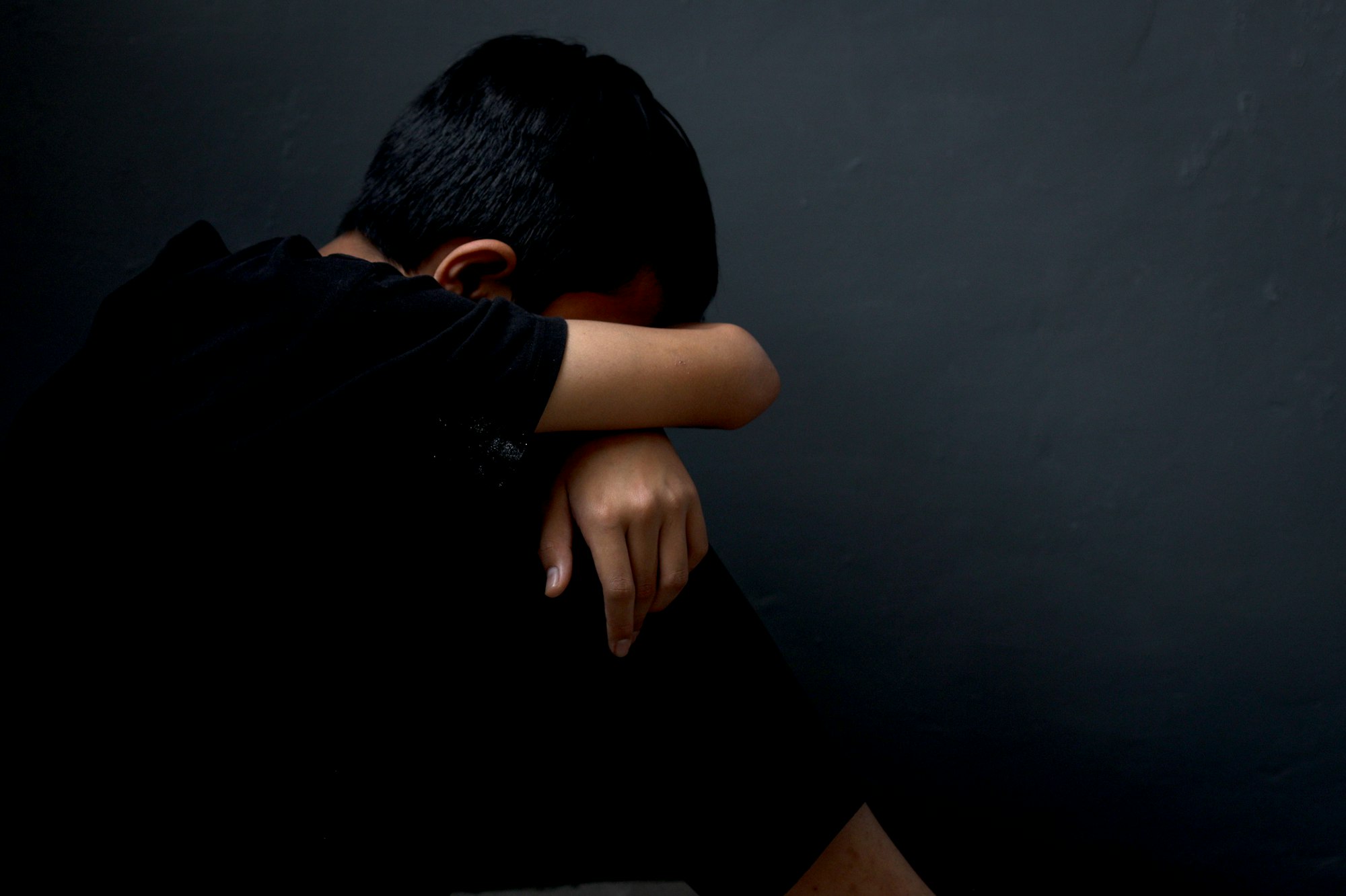 Side view of depressed and lonely boy sitting alone feeling miserable and anxiety