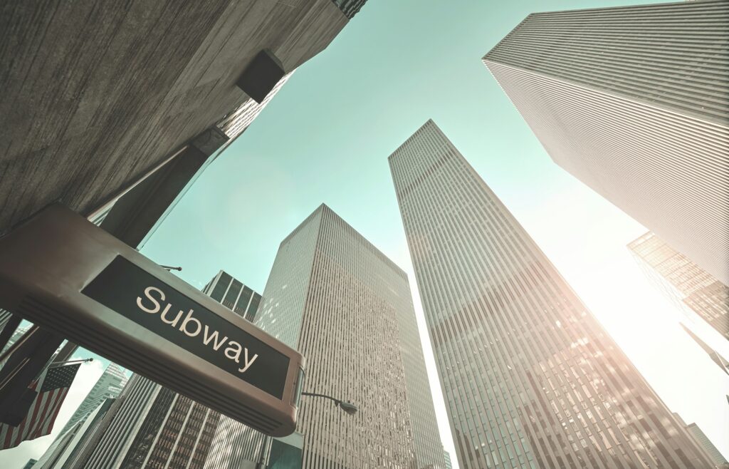 Subway entrance sign and New York skyscrapers.