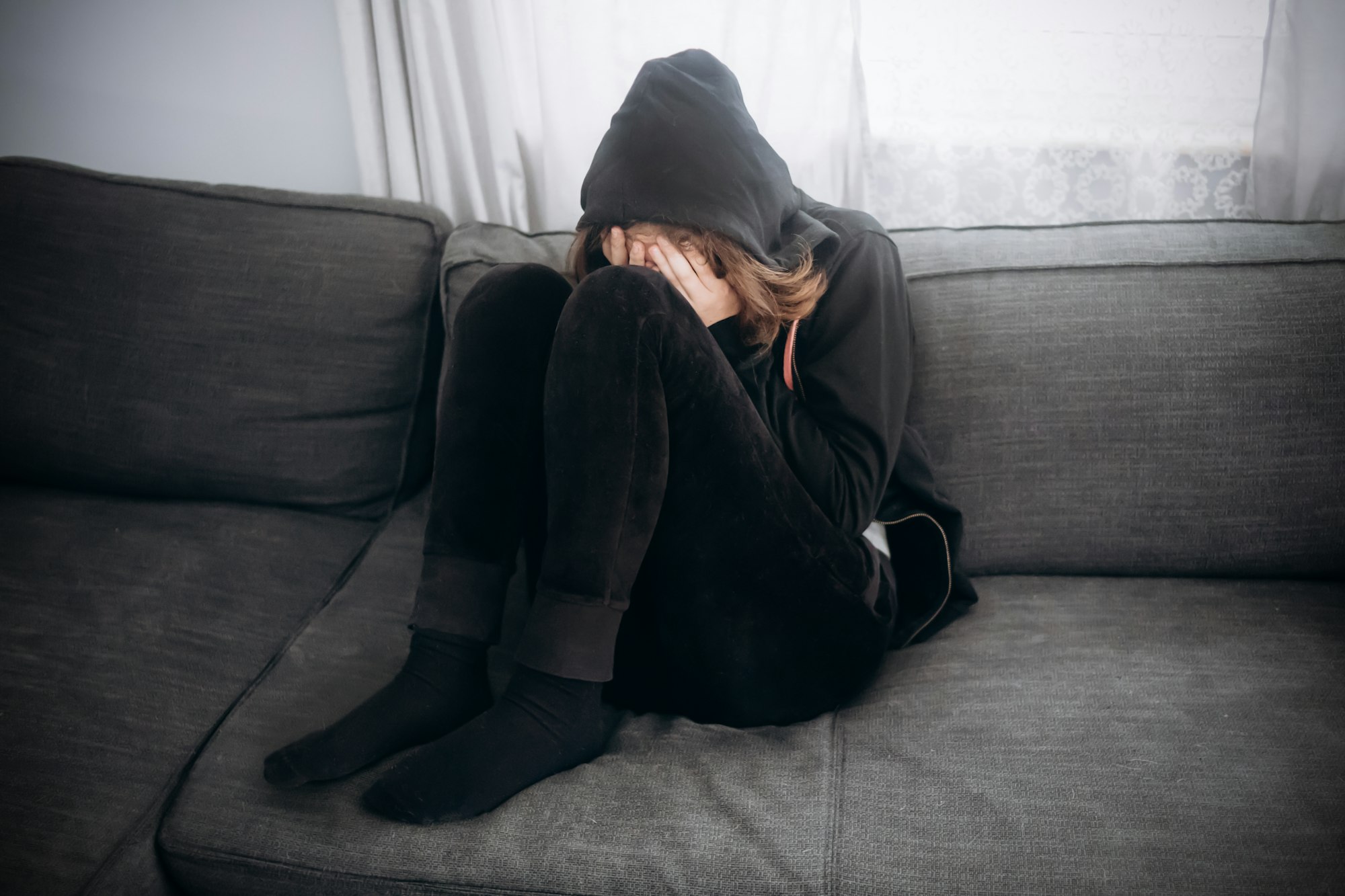 Teenager girl crying on couch. Puberty and depression