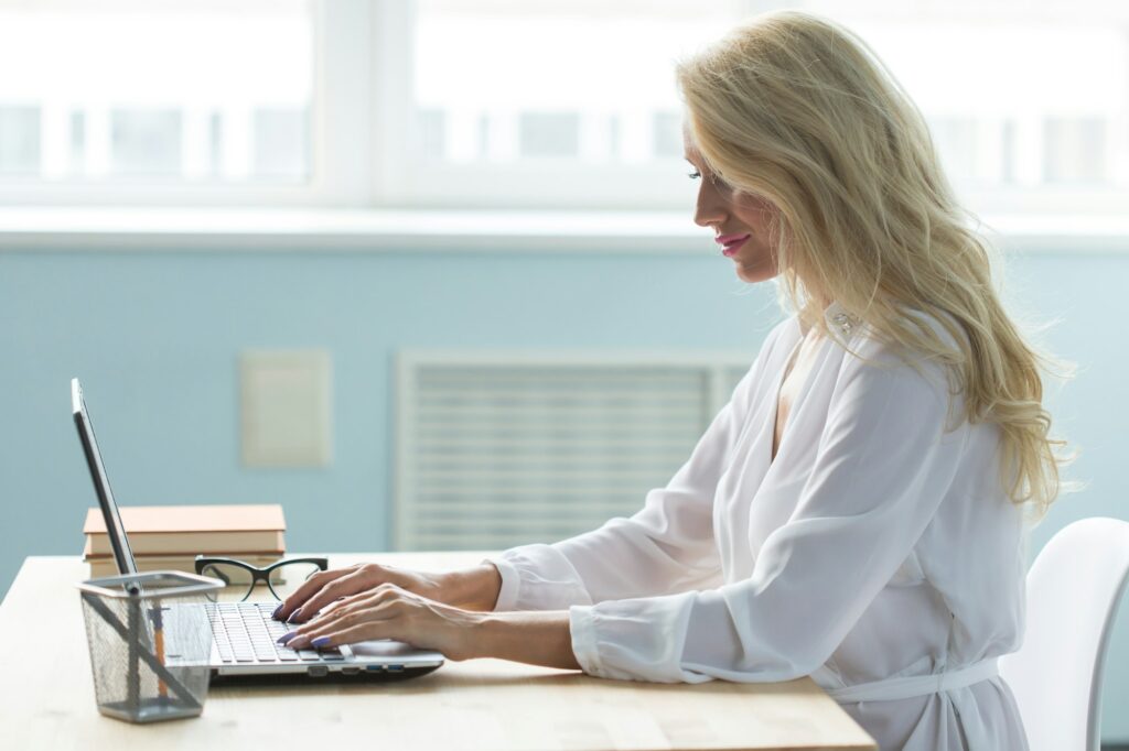 Working, business, technology and people concept - young woman working in office with laptop and