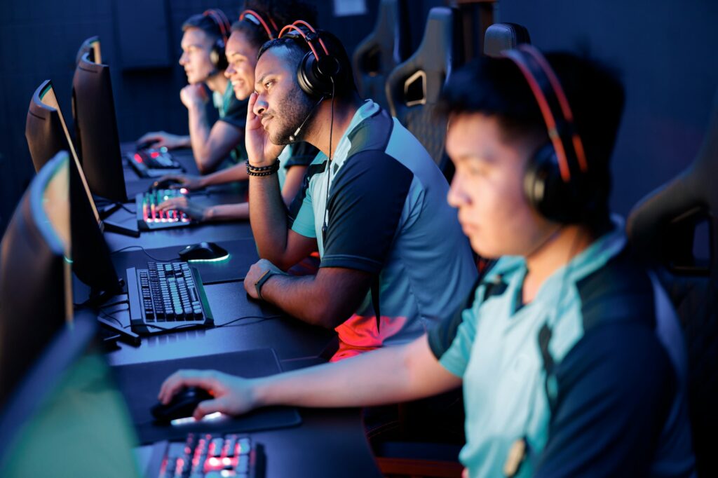 Young gamers in headsets playing in video game club