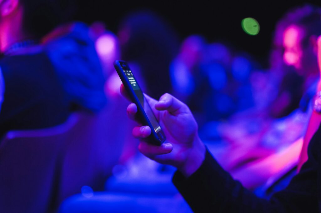 Young man using mobile phone at technology meeting event - Soft focus on front fingers