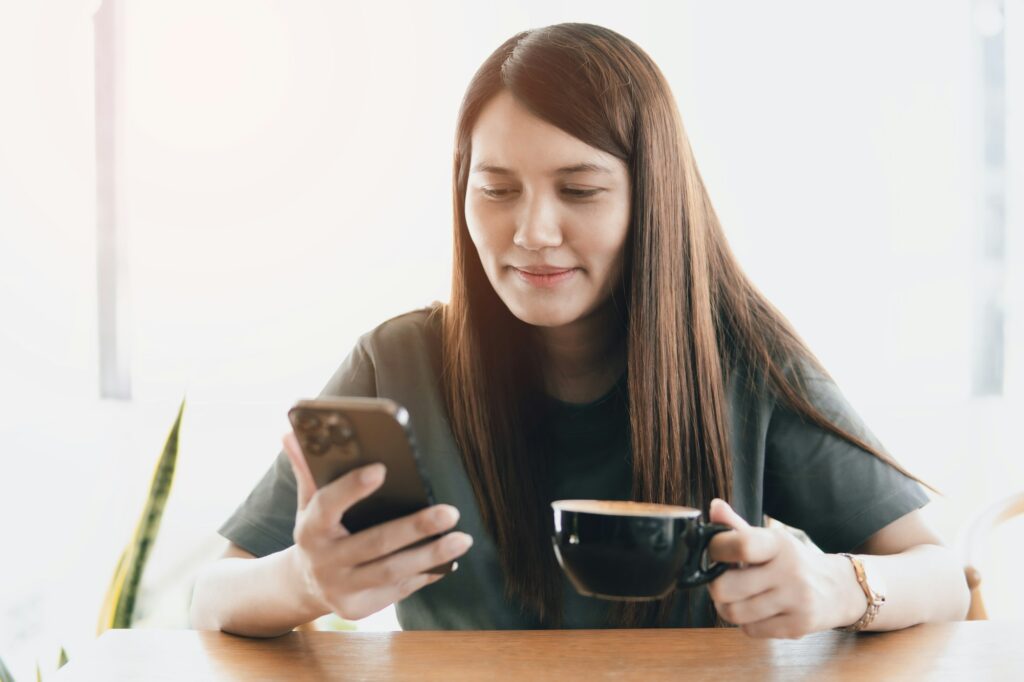 Asia women use smartphone and holding coffee cup in the cafe, lifestyle and online, social network.