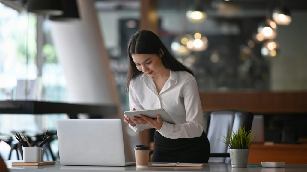 Busy businesswoman working with laptop computer and searching information on digital tablet.