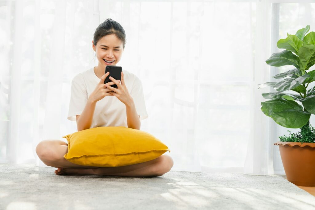 Cheerful beautiful Asian woman holding a smartphone and using online social media on lifestyle