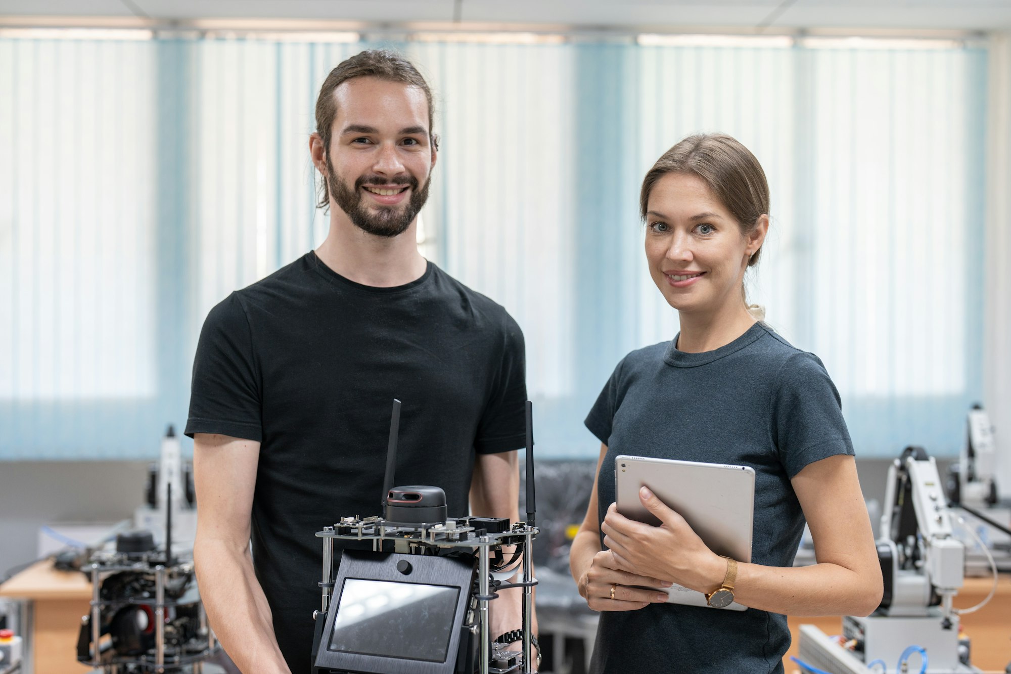 Male and female engineers testing and control AI robot model in the academy robotics laboratory room