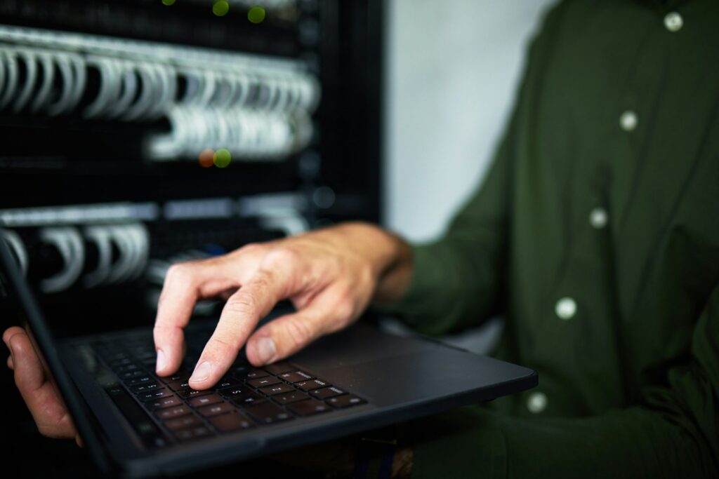 Server room analysis, laptop and technician at work for cyber security and building network. Progra