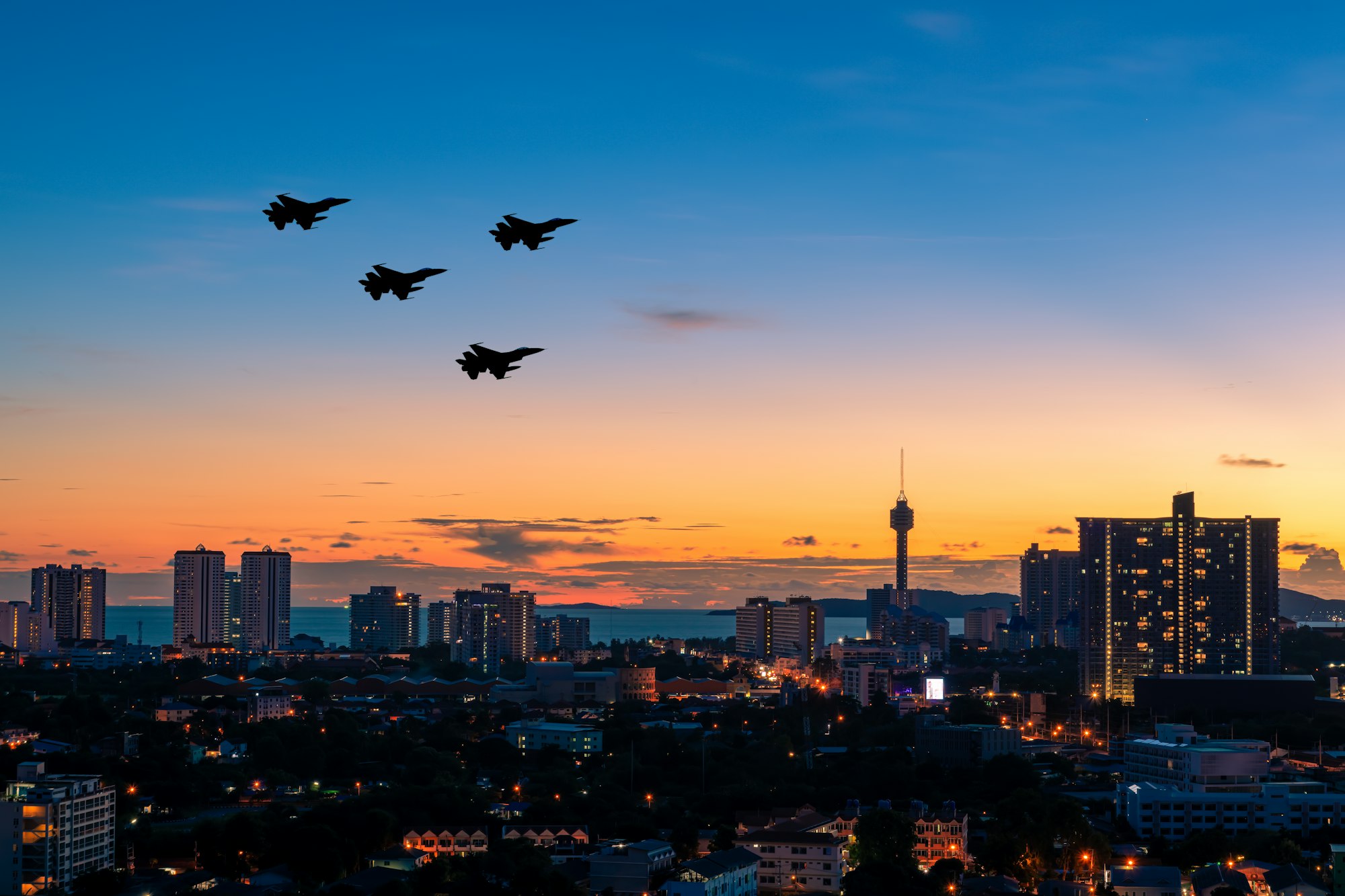 Silhouette team military aircraft flying over city building landscape with beautiful sun sky backgro