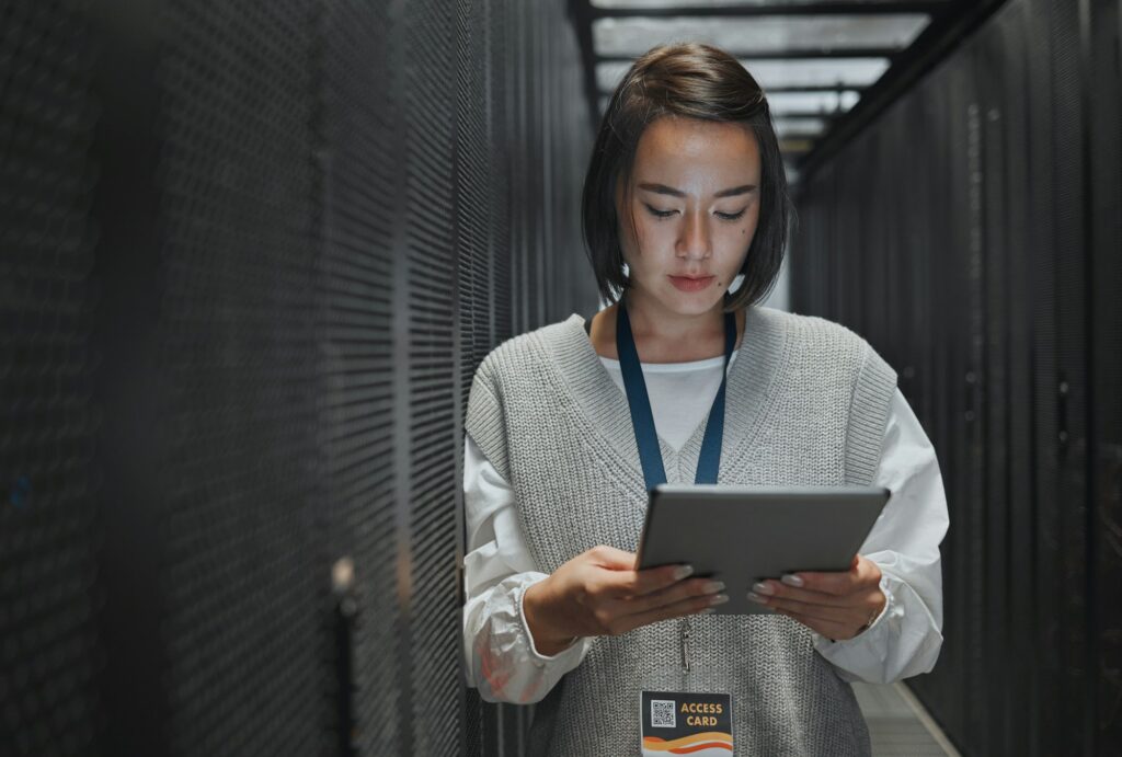 Tablet, server room and cloud computing with a programmer asian woman at work on a mainframe. Softw