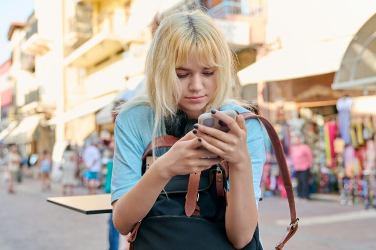 Teenage girl 16, 17 years old with a smartphone in the city.