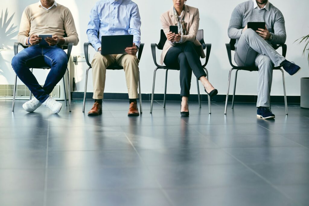 Unrecognizable business people using wireless technology while anticipating job interview.