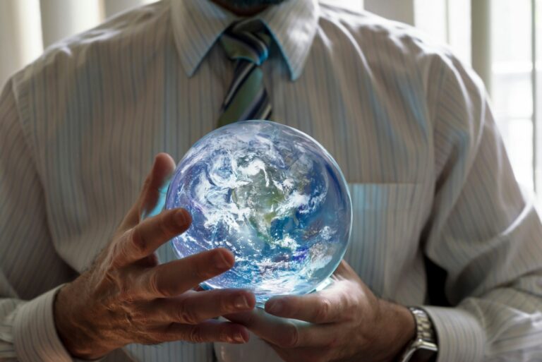 Business person holding an illuminated planet earth in the palms of both hands.