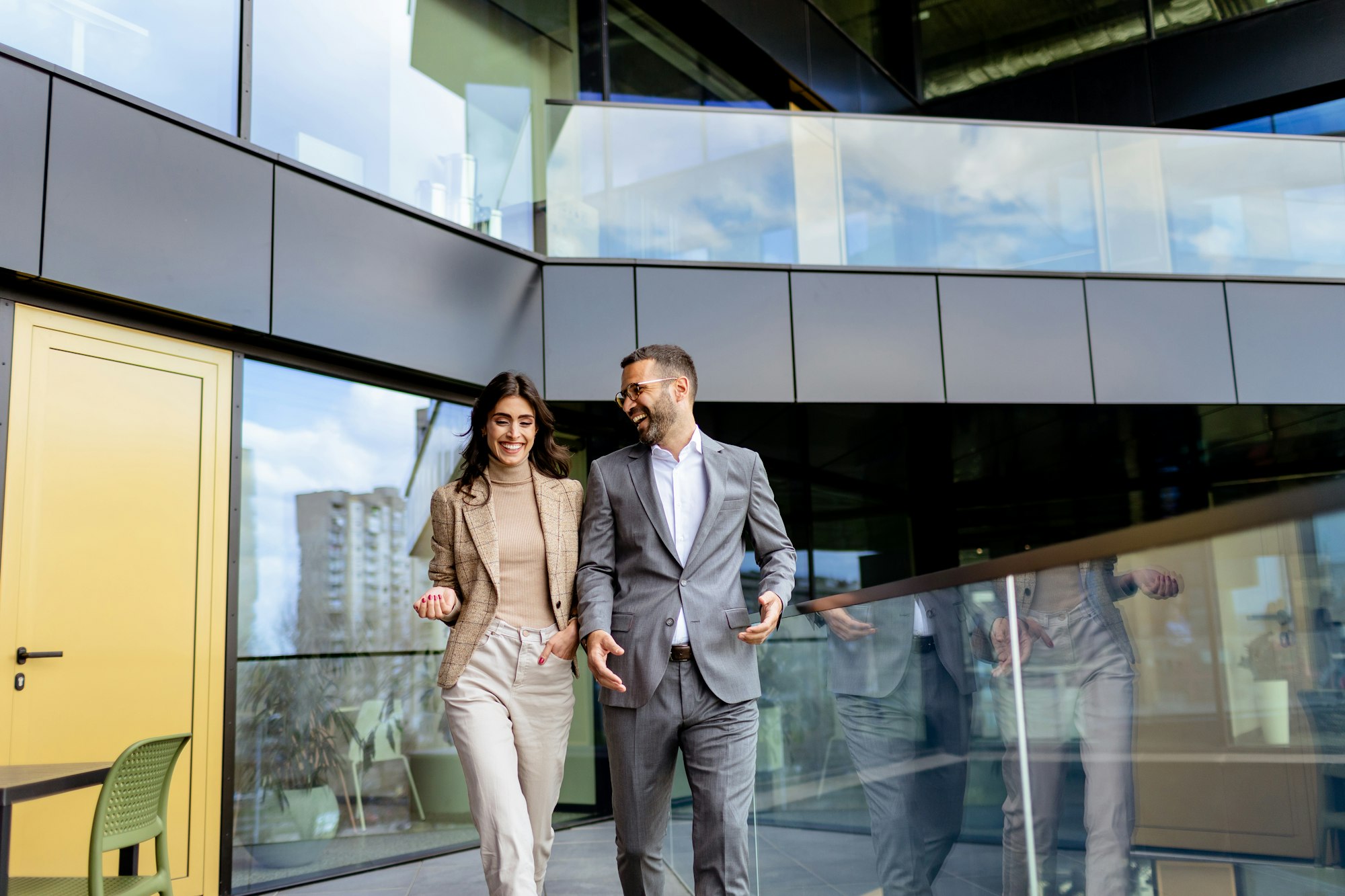 Cheerful Colleagues Exiting a Modern Office Building on a Bright Afternoon. Generative AI