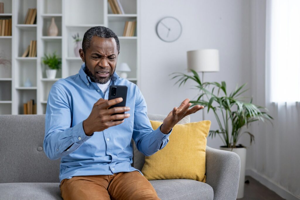 Confused man with phone unable to understand fraud message