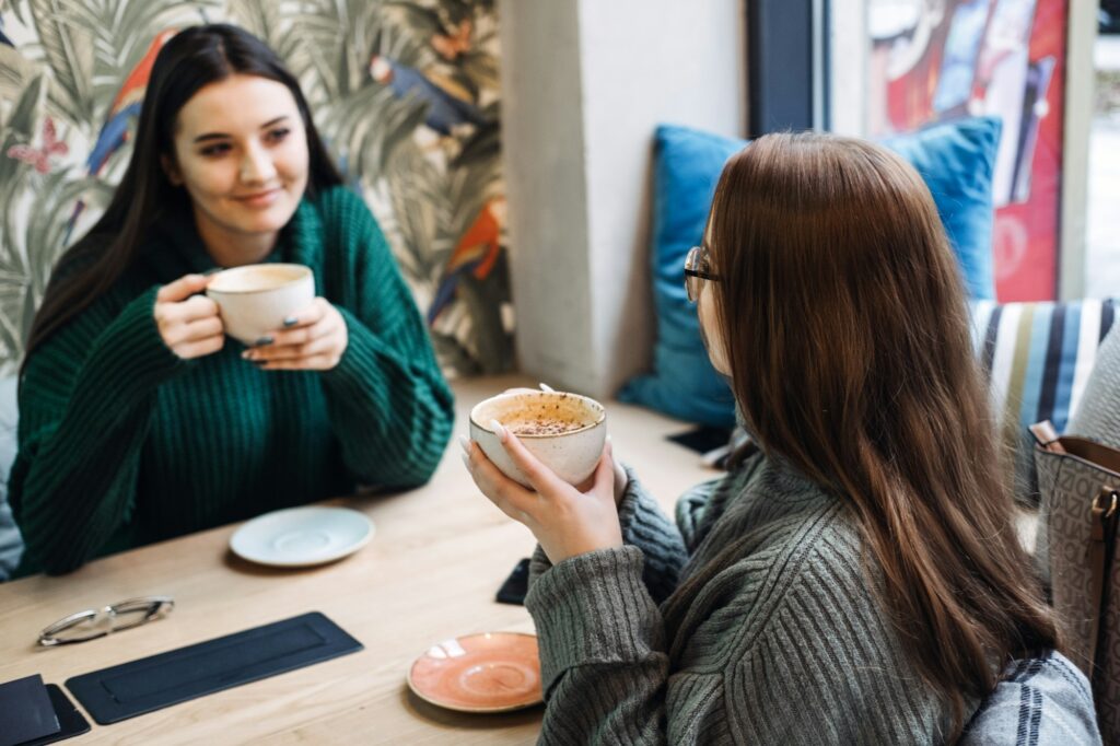 Friends digital detox. Two friends enjoy a face-to-face conversation with coffee in cafe, digital