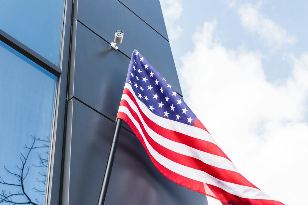 low angle view of national flag of america with stars and stripes near building against blue sky