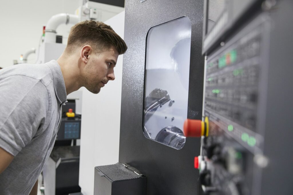 Male Engineer Watching Progress Of CNC Machinery In Factory