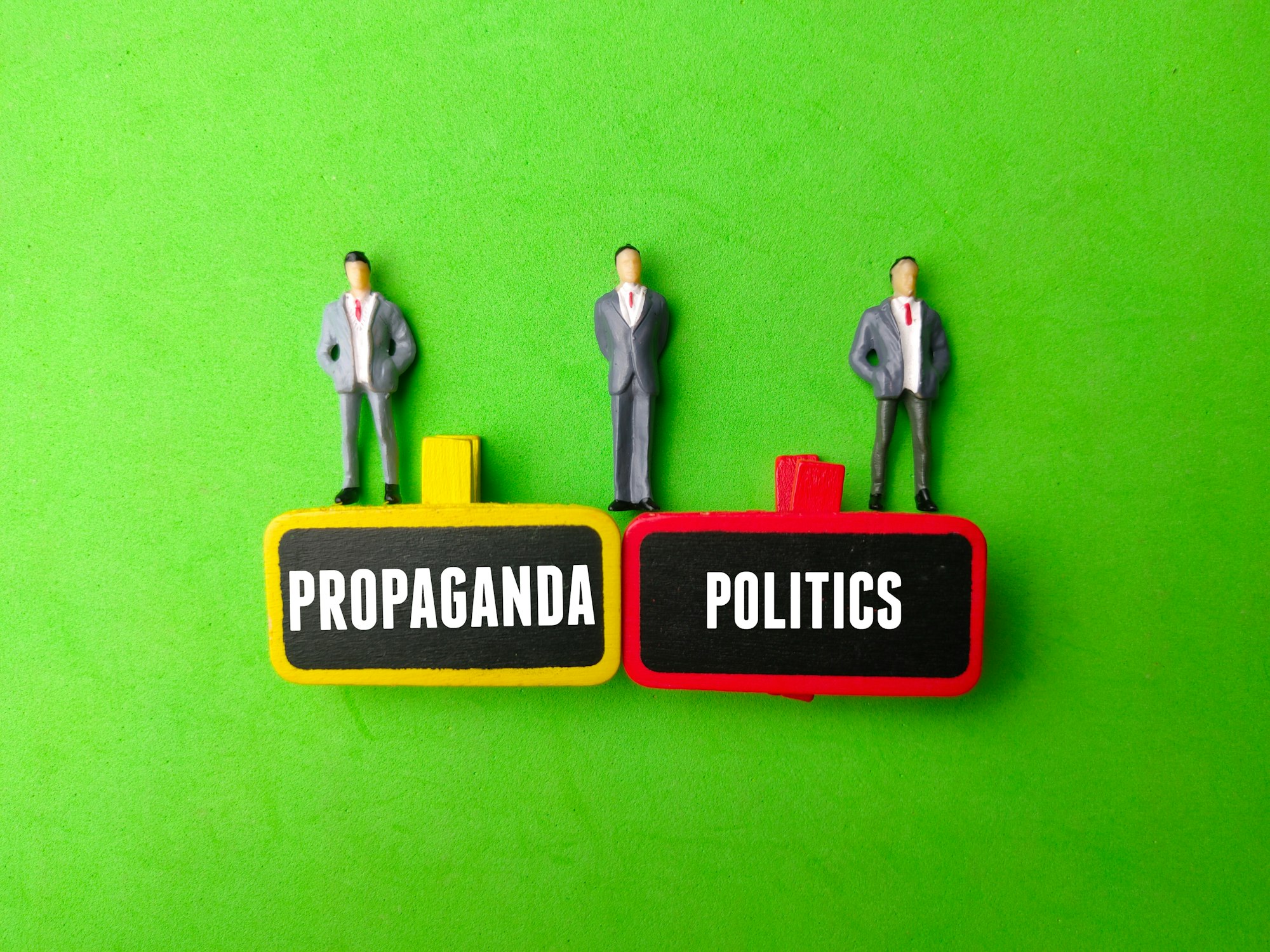 Miniature people and wooden board with the word PROPAGANDA POLITICS