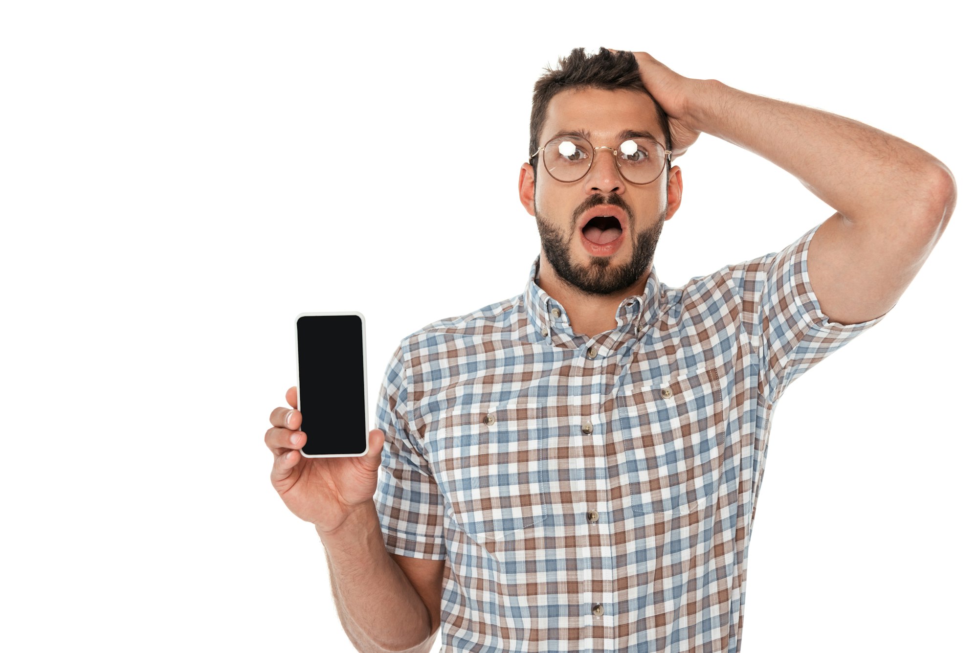 Shocked nerd with hand near head holding smartphone isolated on white