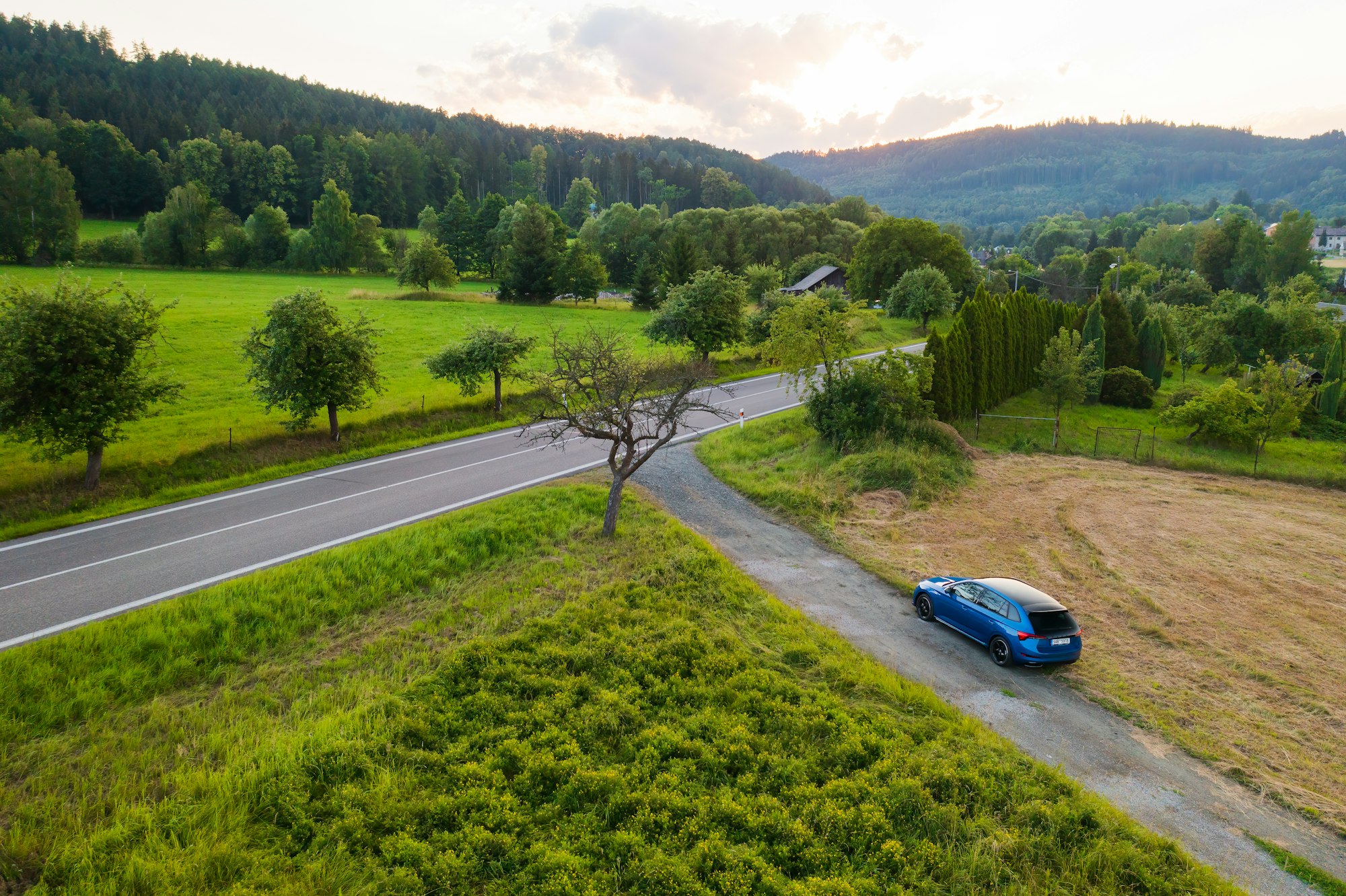 Skoda Scala car standing on the countryside road with amazing view on the valley and lush trees