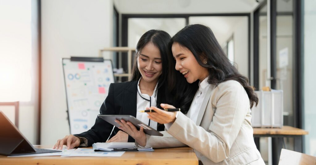 Two young Asian businesswoman discuss investment project working and planning strategy. Business