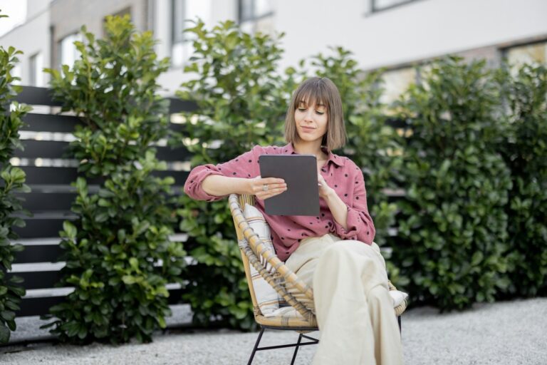 Woman working on digital tablet while sitting relaxed at backyard