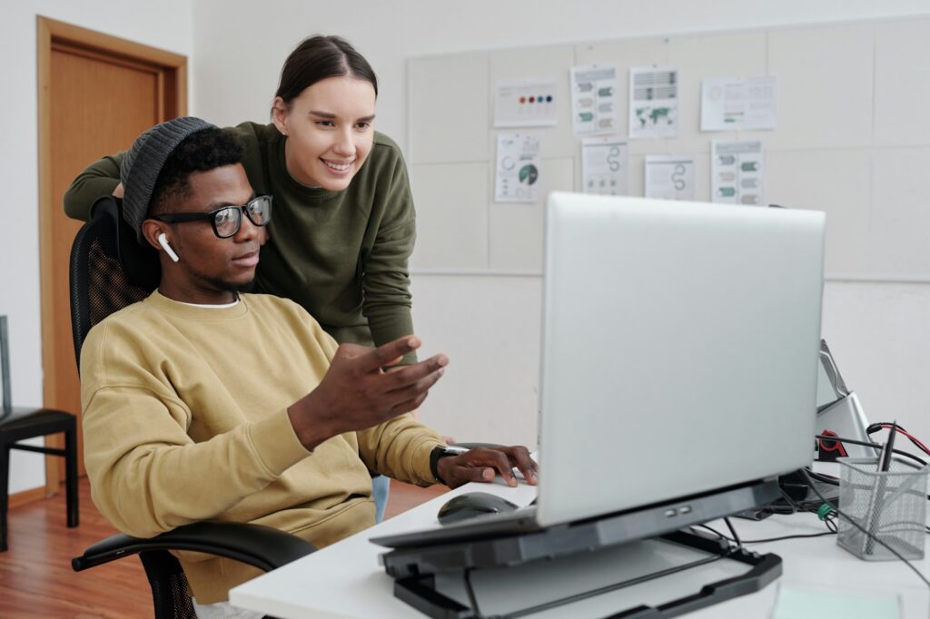 Young male programmer making presentation of decoded language to colleague