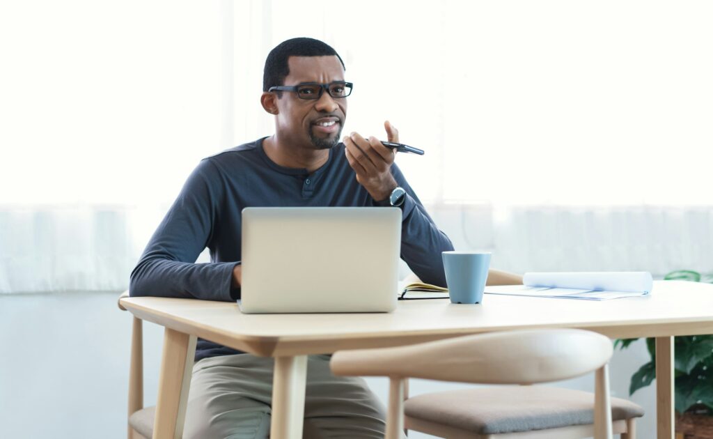 African American bearded freelancer Man records audio message holds phone looks aside.